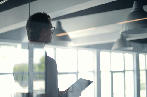 An auditor analyzing energy efficiency data on a tablet in a modern office, highlighting the importance of business energy audits in maximizing air conditioning efficiency.